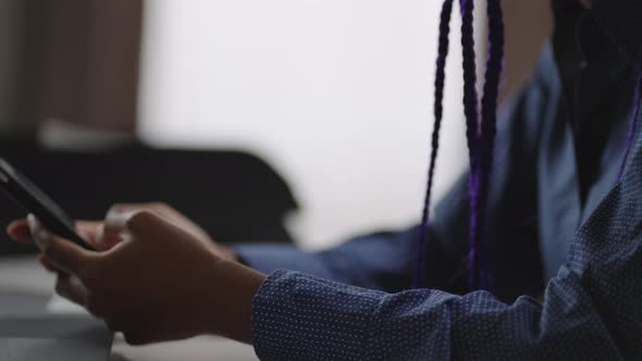 Young Black Woman is Using Modern Mobile Phone in Working Place Closeup of Hands with Gadget alt