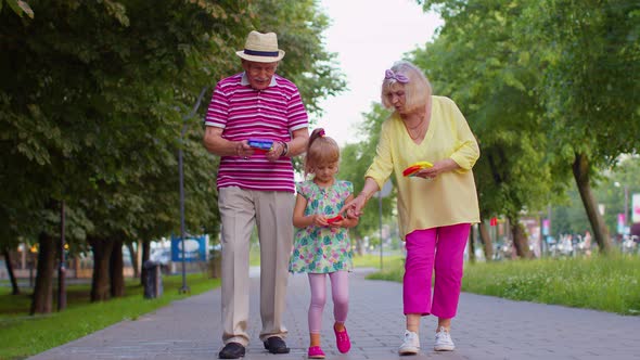 Smiling Senior Grandmother Grandfather with Granddaughter Playing Squeezing Antistress Toy Game alt