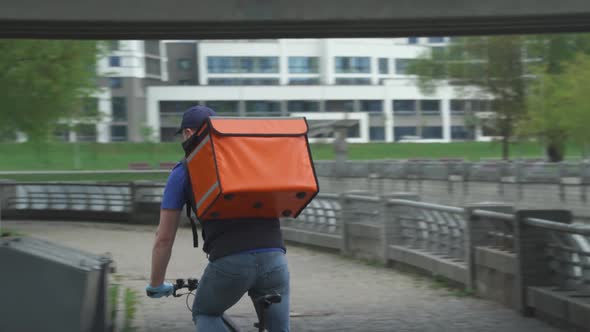 Food Delivery in the Conditions of a Viral Pandemic, Courier in Medical Mask with a Thermo Backpack alt