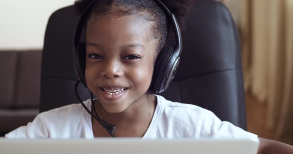Head Shot Close-up Web Cam View of Afro Child Girl in Headphones Speaks Into Microphone, Actively alt