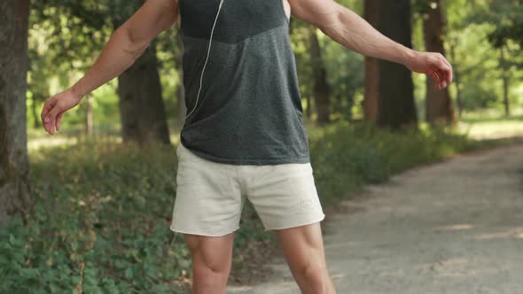 Young Man Warming Up Before Jogging in Park alt