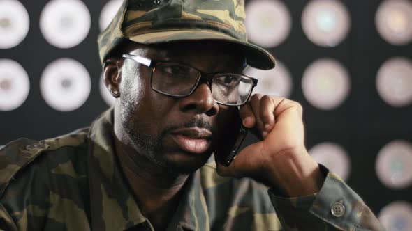 Face of Black Guy in Military Clothes Speaks on Phone Sitting at Desktop