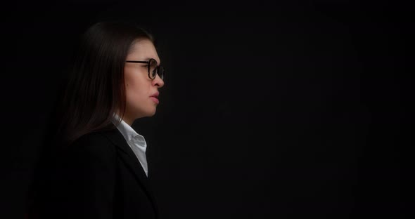 Brunette Stands in Profile Against a Black Background in the Studio and Screams