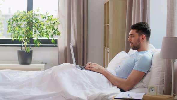 Man with Laptop in Bed at Home Bedroom