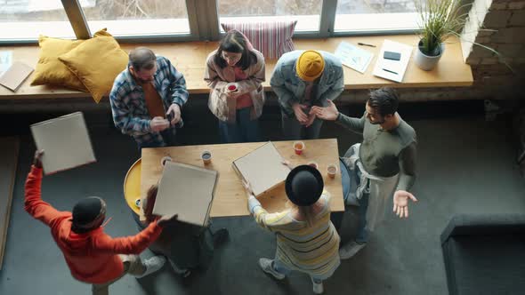 Top View of Joyful Coworkers Bringing Pizza to Office Enjoying Delicious Food Clapping Hands alt