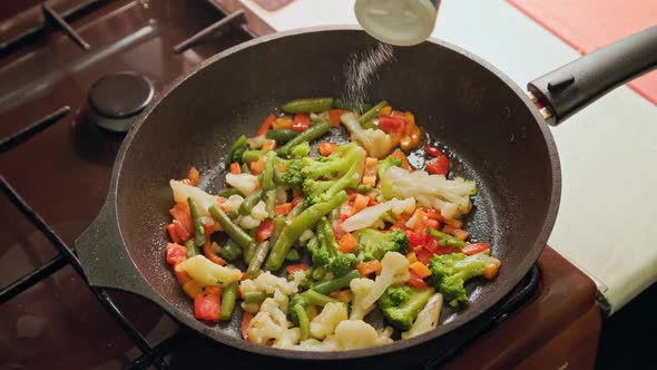 Caucasian Hand Salting Frying Vegetables in a Skillet