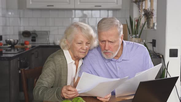 Married Couple of Retirement Age Keeps Accounts Makes an Online Payment Using a Laptop Sitting at alt
