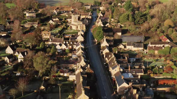 Aerial drone video of a Cotswolds Village, a rural scene in English countryside with houses, propert alt