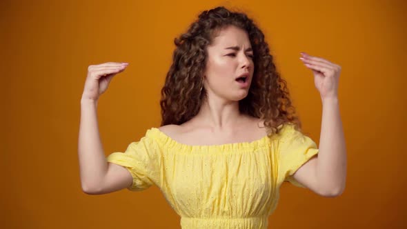 Young Curly Woman Showing Blabla Gesture Isolated on Yellow Background