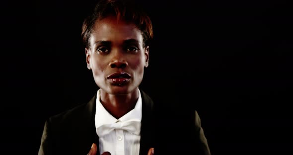 Androgynous man in suit posing against grey background alt