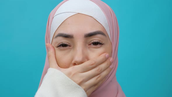 Portrait of Muslim Woman in Hijab Removing Hand From Her Mouth and Smiling at Camera in Studio