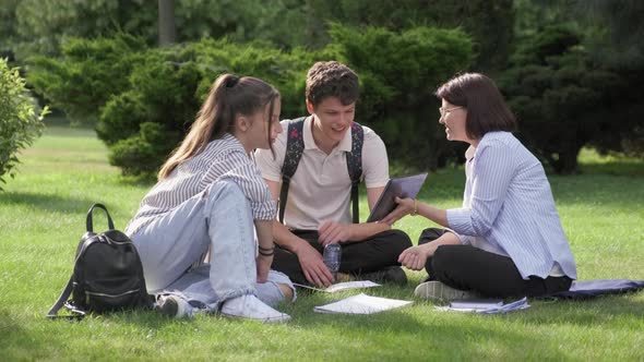 School Teacher Psychologist Social Worker Talking to Teenagers Sitting on Grass alt