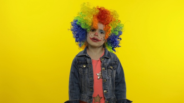 Little Child Girl Clown in Rainbow Wig Making Silly Faces, Fool Around, Smiling, Dancing. Halloween alt