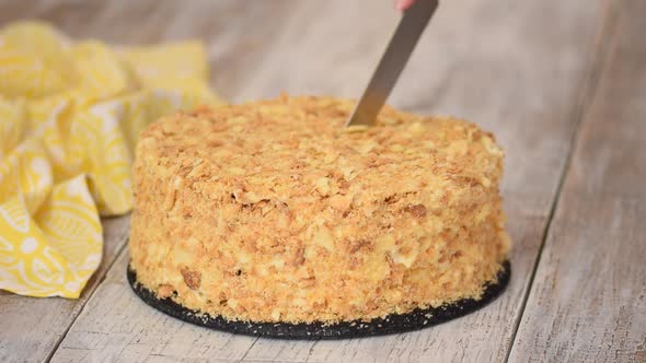 Hands Cutting Knife a Cream Puff Cake Napoleon Sprinkled Crumbs alt