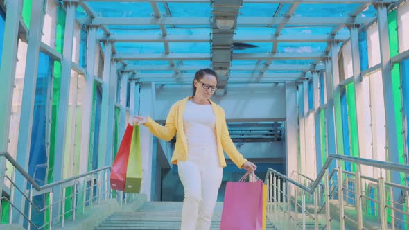 Joyful woman with purchases goes down stairs alt