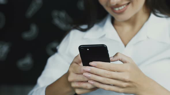 Close-up Woman Using Phone Indoor and Smiling alt