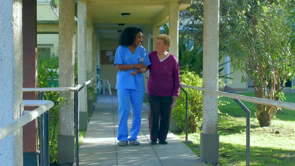 African Doctor Helps Elderly Woman To Walk in a Hospital Rehab Garden alt