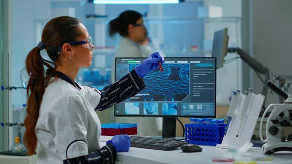 Laboratory Doctor Holding at Blood Sample and Typing on Computer alt