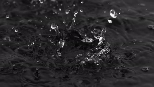 Super Slow Motion Shot of Water Drops Falling Into Water on Black Background at 1000 Fps. alt