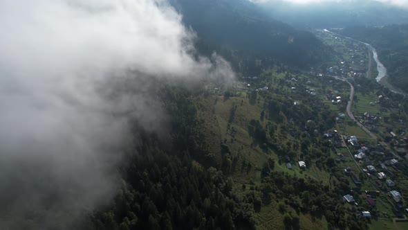 Flying Over the High Mountains with Pine Forest in Beautiful Clouds