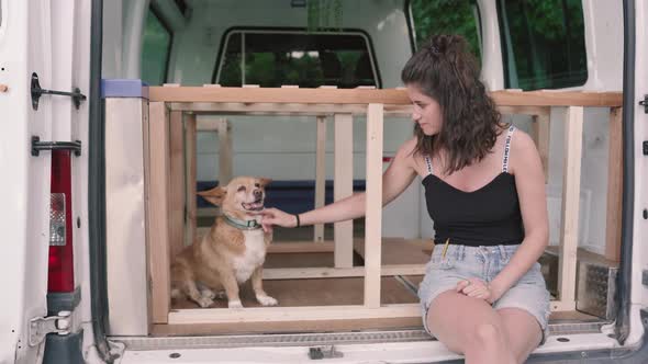 Pretty young woman with dog resting in camper van,close up. Preparation for holiday trip. alt