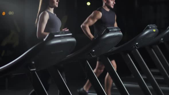 Wellness Female and Man Athlete Run on a Treadmill Two Runners Perform Aerobic Exercise and alt