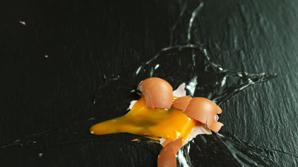 Super Slow Motion Shot of Falling and Breaking Whole Egg on Black Table at 1000 Fps. alt