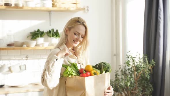 Closeup of a Woman Holding a Large Bag of Fresh Vegetables at Home in the Kitchen