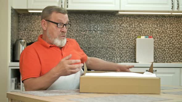 Happy Elderly Man Unpacks a Parcel alt