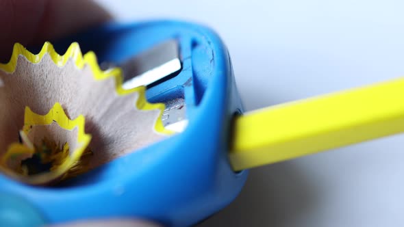 Yellow Wooden Pencil Shavings Coming Out From Blue Sharpener Closeup View alt