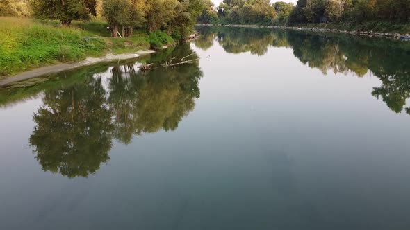 Drone flies just above the water surface, over Adda river in Italy alt