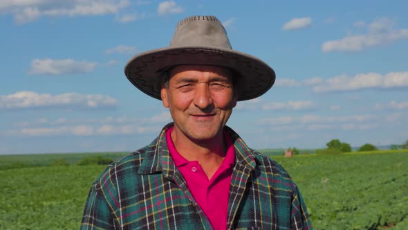 The Portrait of a Male Farmer in a Plaid Shirt with a Hat on His Head is Satisfied alt