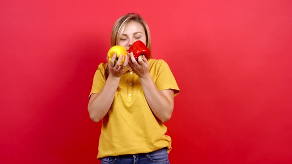 Cute and Slightly Fat Girl in a Yellow T-shirt Holding a Yellow and Red Pepper in Her Hand. alt