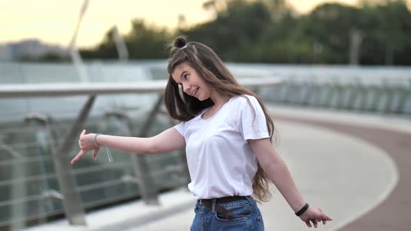 Pretty Teen Girl Cheerfully Dancing on Footbridge alt