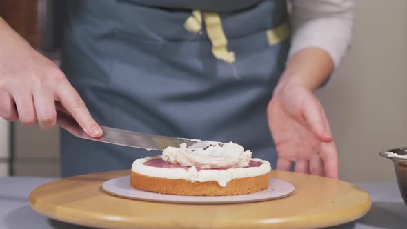 The Pastry Chef Applies the Cream To the Berry Layer Between the Biscuits alt