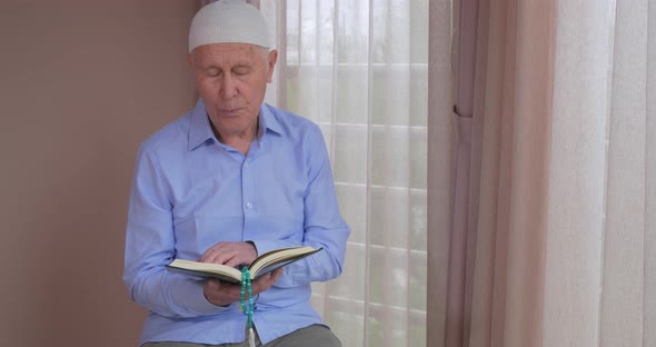 An Old Muslim Man Reading Koran at Home