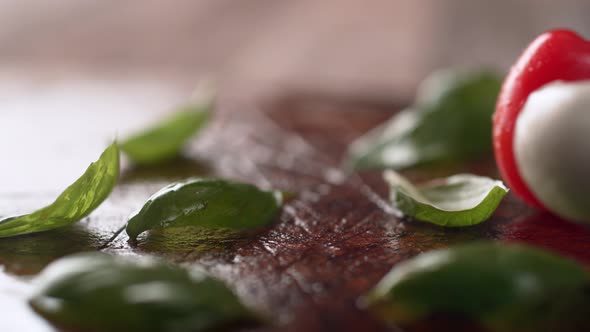 Cherry tomato and mozzarella cheese rolling over fresh basil. Slow Motion. alt