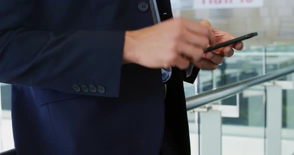 Businessman using smartphone in modern office building alt