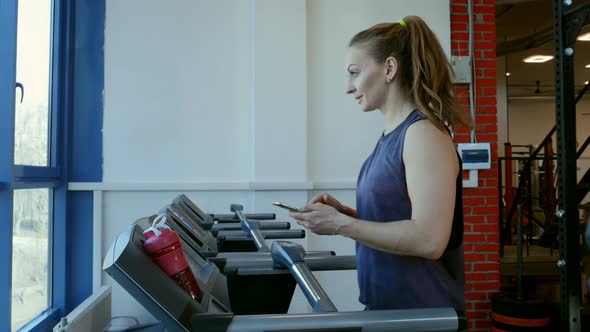 Attractive Young Sports Woman is Working Out in Gym, Doing cardio Training on Treadmill
