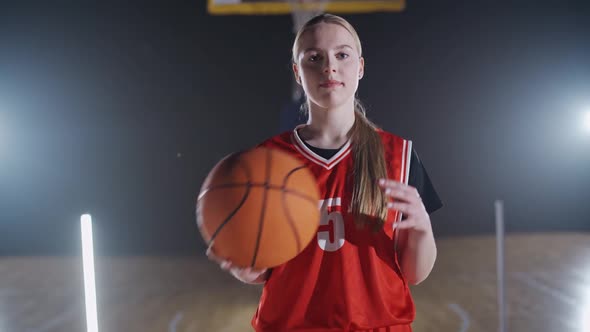 Portrait of a Young Female Basketball Player Holding a Ball in Her Hands and Looking at the Camera alt