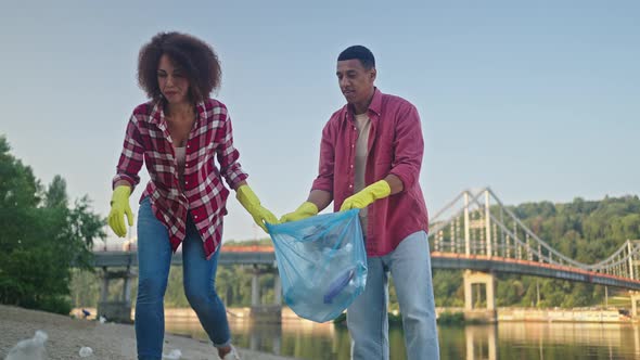 African American Volunteers Remove Plastic Bottles on Beach alt