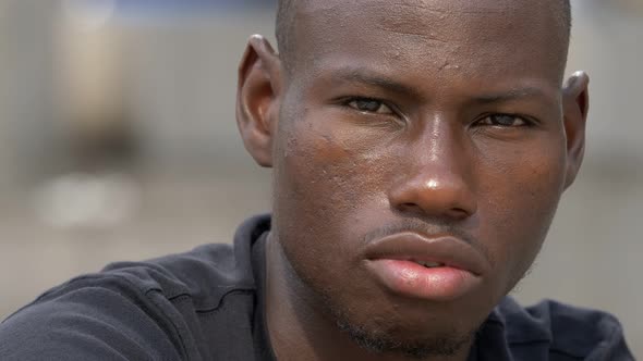 Thoughtful proud youn black african man staring at camera,closing his eyes alt
