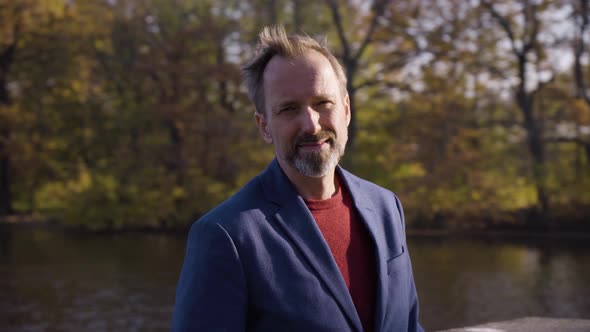 A Middleaged Handsome Caucasian Man Smiles at the Camera on a Bridge in Fall