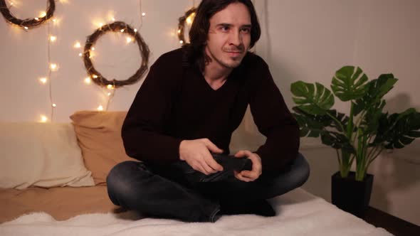 A Man Plays a Game Console with a Joystick