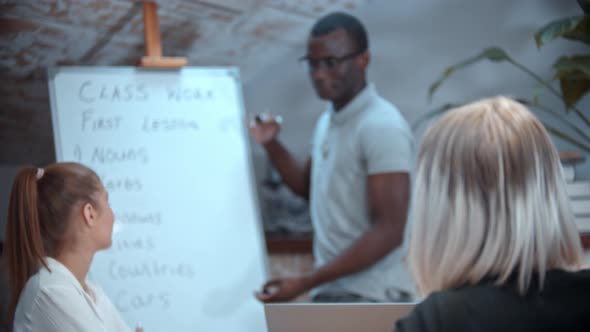 English Lesson in the Class with an African American Teacher - Two Women Sitting By the Table and alt