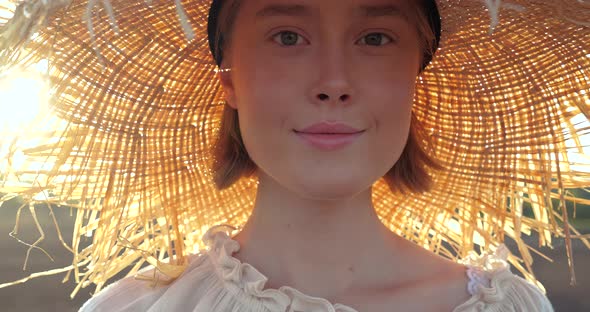 Front View of young Blonde Girl is walking in Sunny Day on Field, Village.