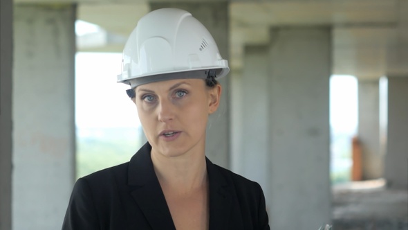 Construction female worker on building site talking to camera