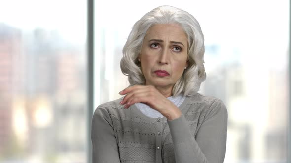 Portrait of Upset Mature Woman on Blurred Background. alt