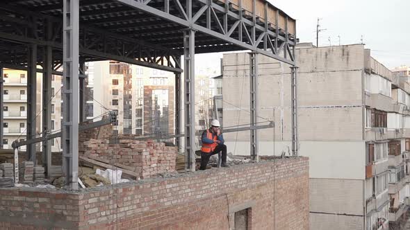 The foreman at the construction site controls the process using a walkie-talkie. alt