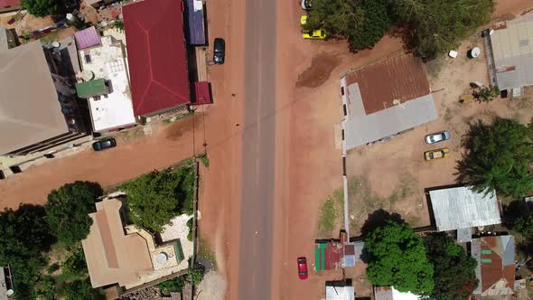 Rising flight towards Kololi road junction in Serrekunda Africa with traffic and people crossing and alt